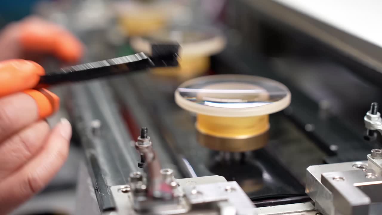 A close-up of a worker drawing black ink on the edge of the glass