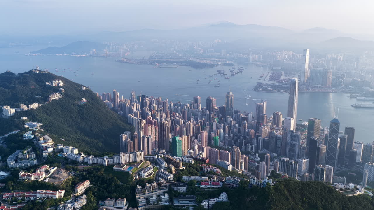 Cinematic aerial view of Hong Kong skyline shrouded in mist at blue hour, with glowing skyscrapers and Victoria Harbour fading into a moody, atmospheric twilight