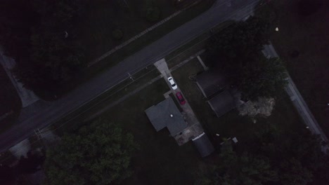 aerial drone bird's eye view over cars parked infront of a small town home during evening time