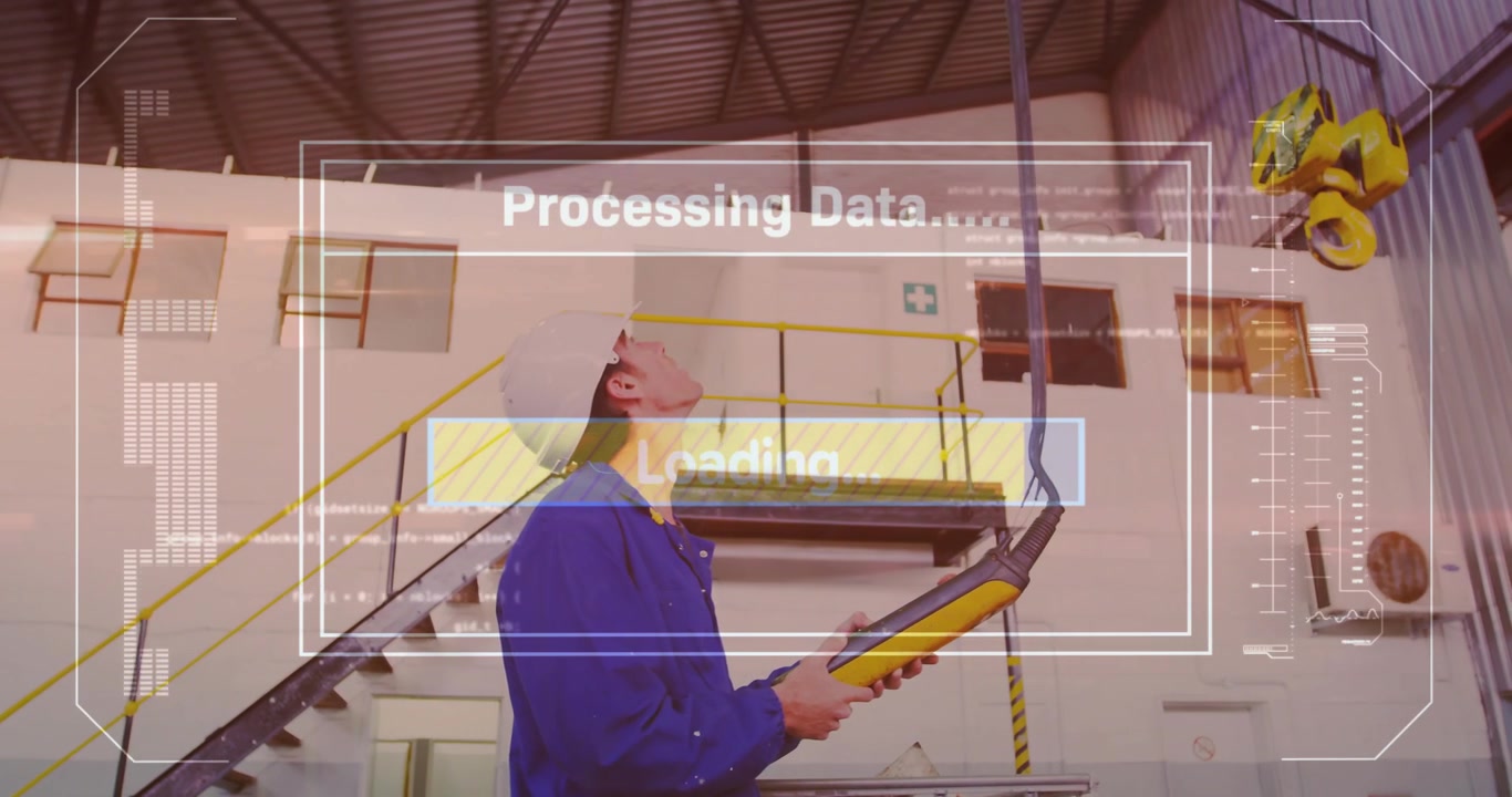 Male technician pressing yellow pendant in factory, loading HUD and guiding crane hook overhead