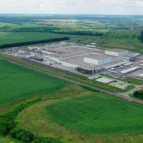 large industrial zone on green field. factory surrounded by beautiful landscape in summer. aerial view. camera moving back