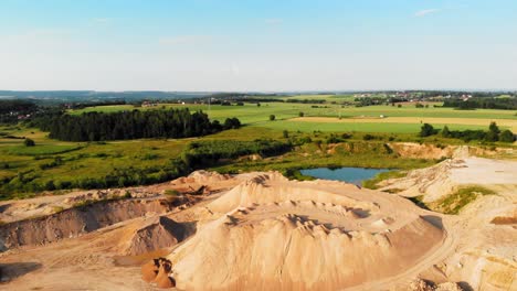 Aerial-dolly-shot-of-dunes,-pits-and-a-meadow-in-a-quarry,-showing-contrast-between-nature-and-industry-