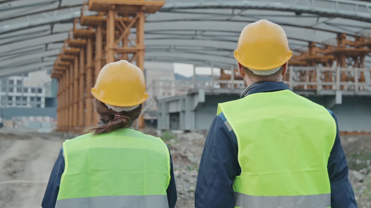 Rear View of Construction Workers Talking and Walking