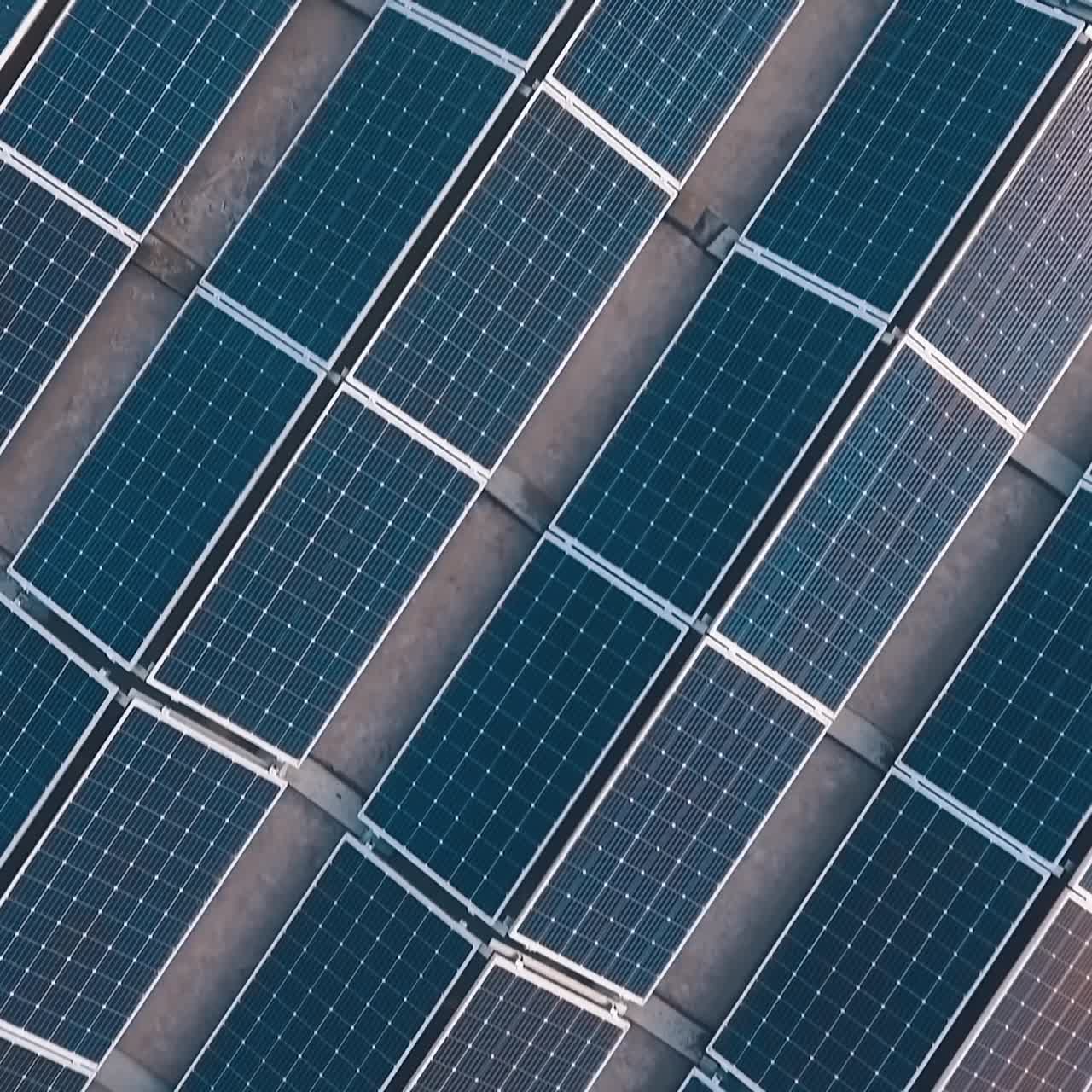 Sorvolando il parco solare con riflessi di sole sui pannelli. Pannelli solari fotovoltaici fissati a terra. Nuova fonte di energia. Vista dall'alto.