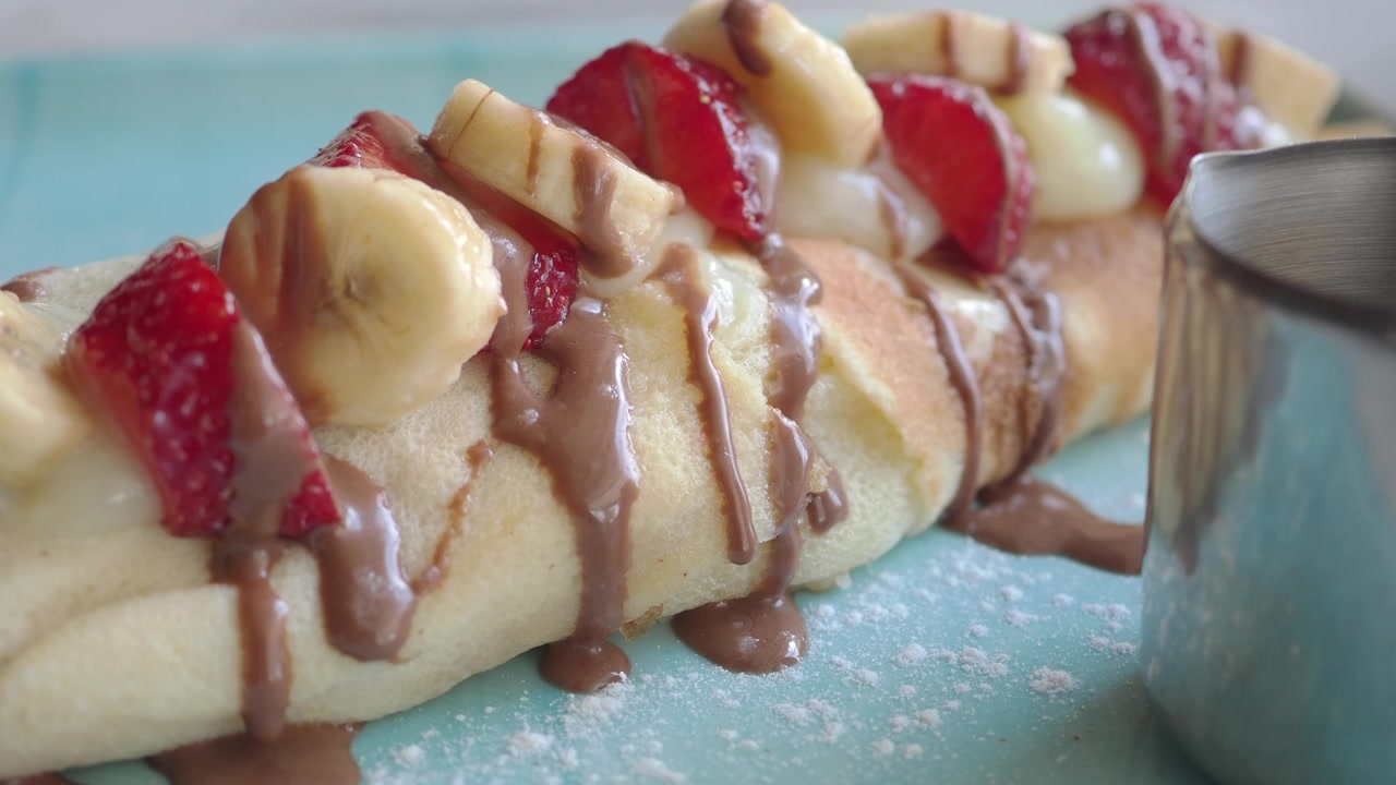 Deliziosa crepe guarnita con fragole fresche, banane e salsa al cioccolato.