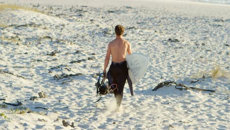 Männlicher-Surfer,-Der-Mit-Surfbrett-Am-Strand-Spaziert-4k