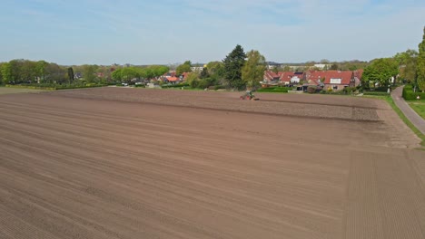 Calm-aerial-of-tractor-plowing-a-empty-plot-of-land-at-the-edge-of-town