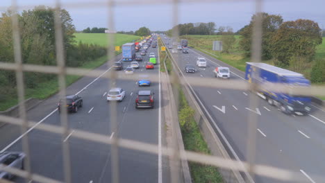 busy motorway with lane closure, view through mesh fence