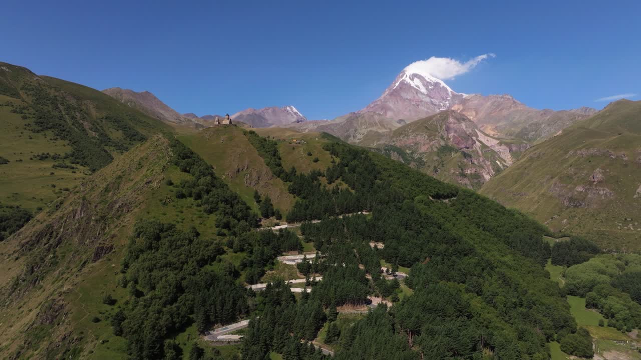 carretera sinuosa con cruces hacia la iglesia de la trinidad de gergeti, monte kazbek, georgia