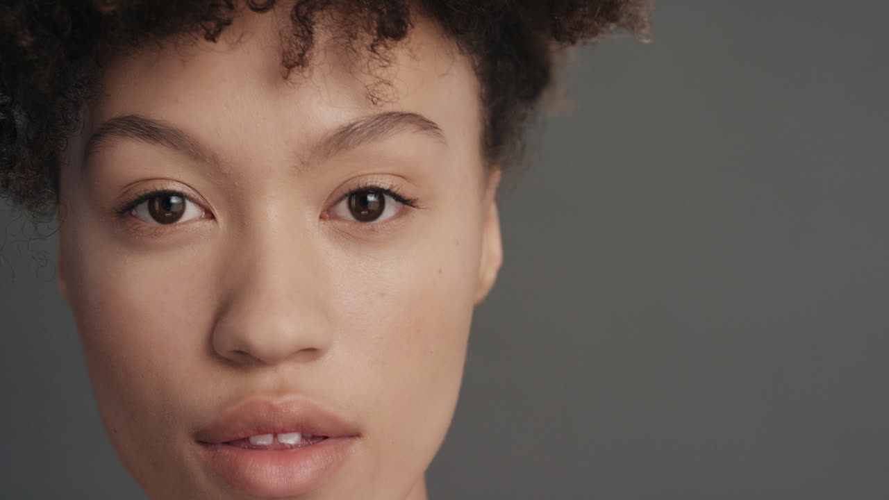 retrato de cerca hermosa mujer joven de raza mixta con una piel perfecta y saludable con aspecto confiado belleza sensual en fondo gris concepto de cuidado de la piel