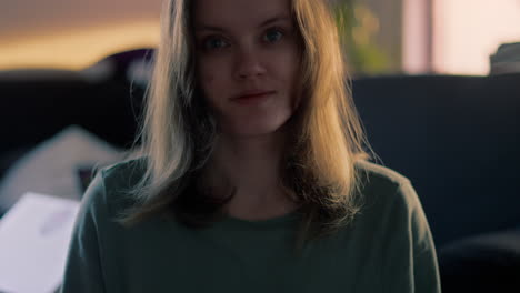 cinematic close up of a white young woman smiling and blowing a kiss straight into the camera during a golden hour at sunrise in her apartment in slow motion