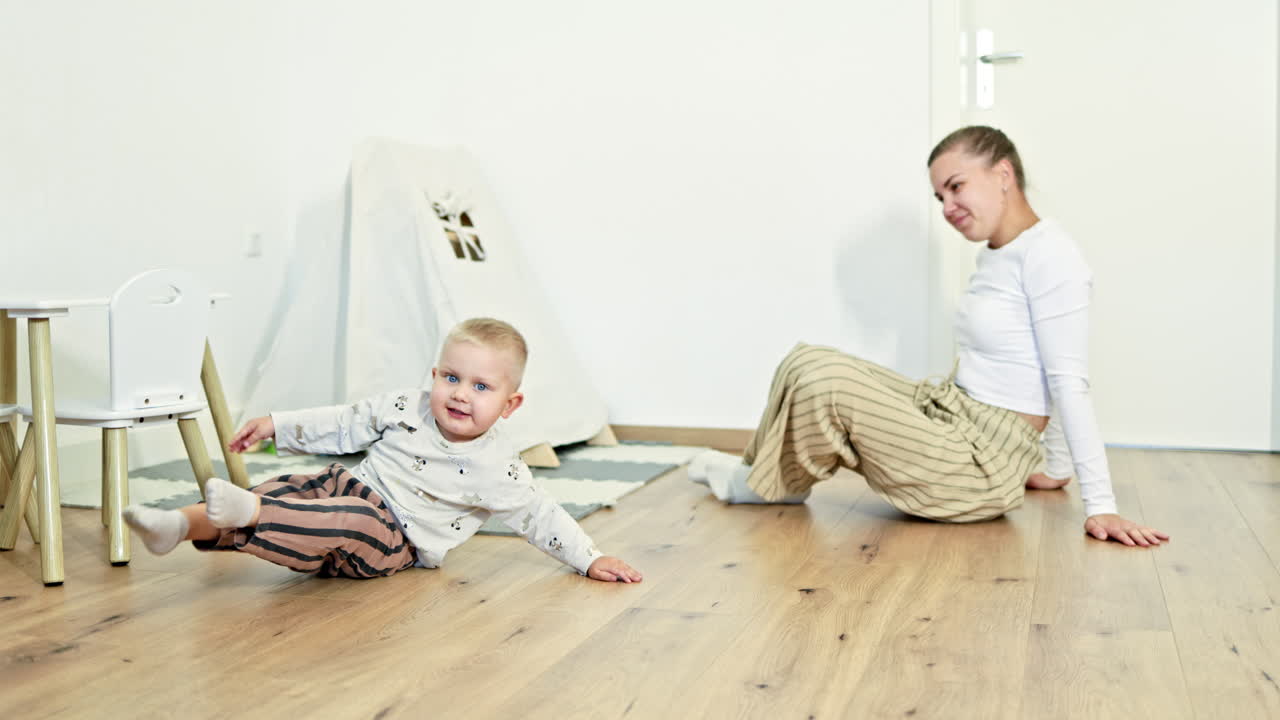 Madre amorevole che gioca con suo figlio in un luminoso soggiorno. Il bambino gioca con la sua mamma allegra. La madre in congedo di maternità si dedica allo sviluppo del figlio. Famiglia felice.