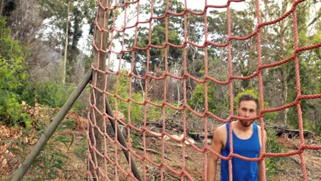 fit man climbing a net during obstacle course