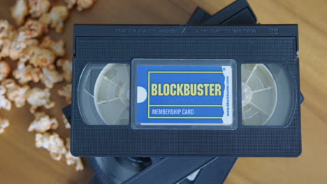 close up pan right shot of a blockbuster membership card with vhs tapes and popcorn