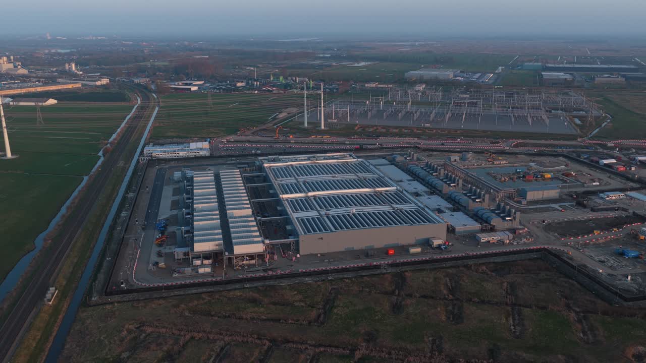 High angle perspective showing a large data center complex during its construction phase, featuring solar panels installed on the roof