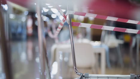 chairs legs with warning strip in closed cafe and guy runs