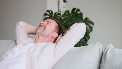 relaxing at home, senior man smiling with hands behind head on couch