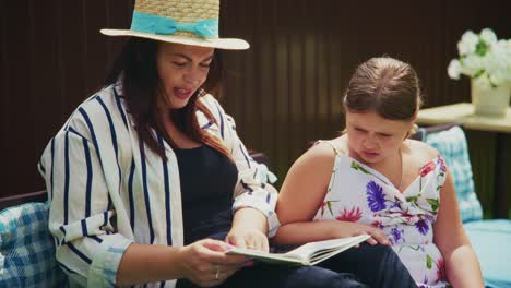 woman and girl enjoying a storybook together outdoors in a cozy, relaxed setting with bright sunlight