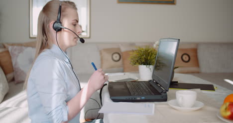 sales representative in headset speaking to client and making video conference call on laptop 12