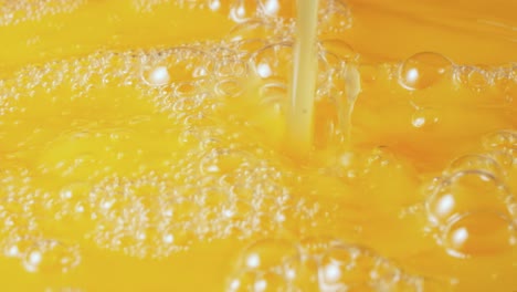 a stream of freshly squeezed natural orange juice poured into glass a stream of freshly squeezed natural orange juice poured into a glass exotic yellow citrus nectar or lemonade in a glass on a blue background diet healthy tropical breakfast drink slow motion close up