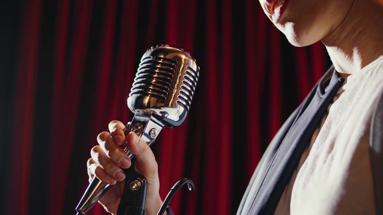 Primo piano di un cantante che tiene un microfono vintage su un palco