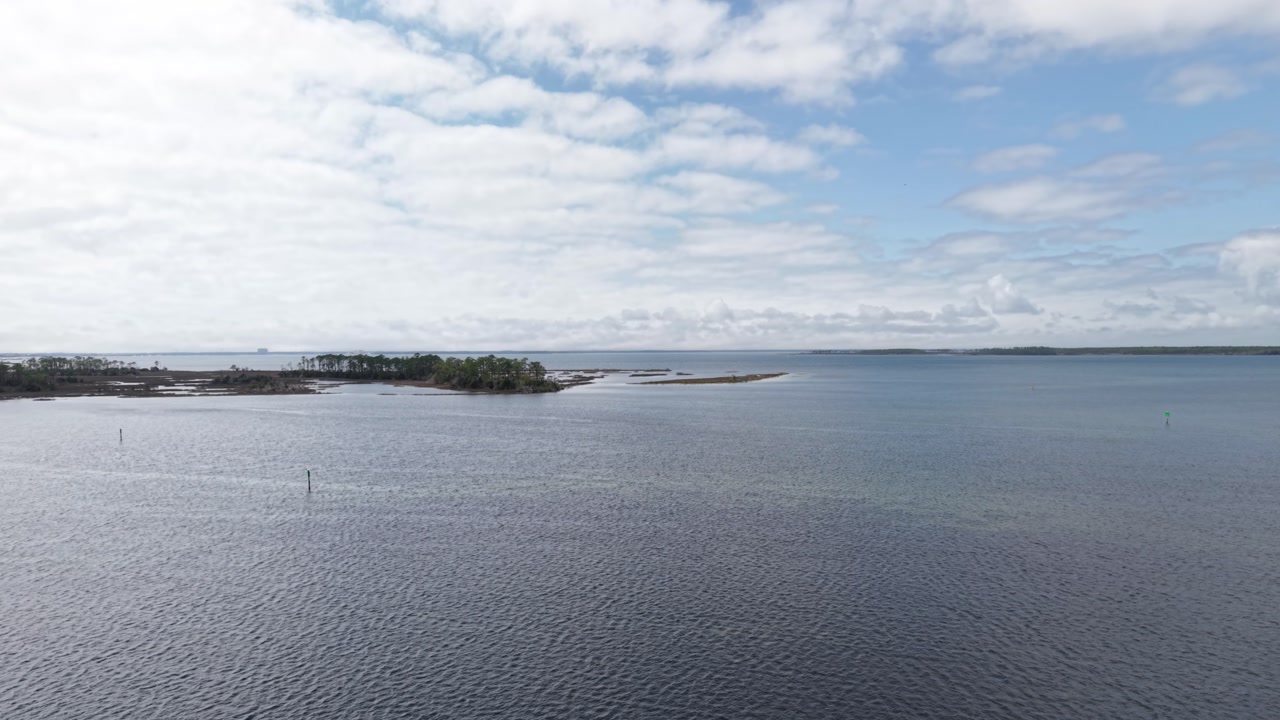 Drone fly of coastal Grand Lagoon with long wooden pier on still water, Lynn Haven, Florida, USA