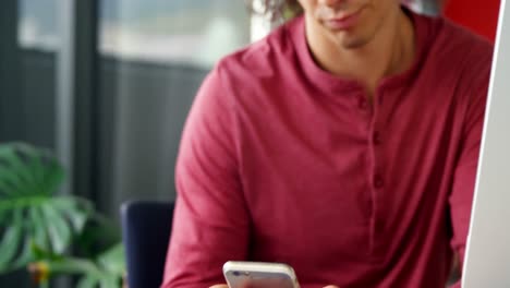 Business-executive-using-mobile-phone-while-working-on-desk