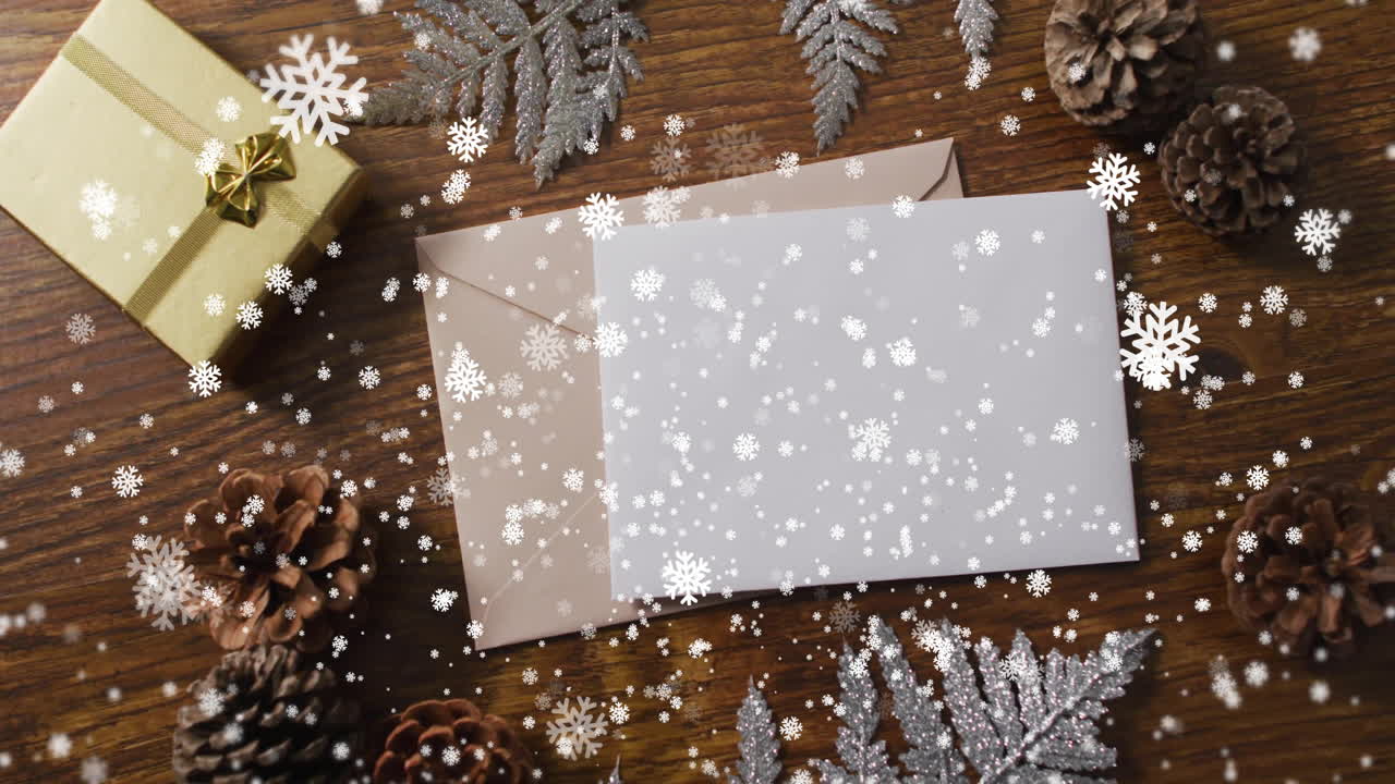 Animation of christmas decorations with card with copy space over snowflakes on wooden background
