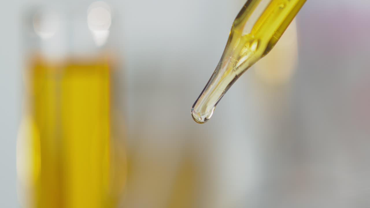 gotero de pipeta con goteo de líquido amarillo vibrante y fondo borroso