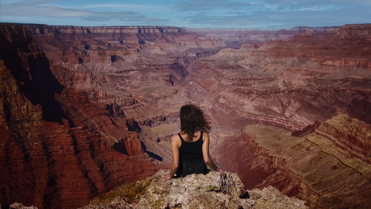 Grand Canyon National Park cinemagraph with young woman sitting on cliff edge. Wind moving her hair