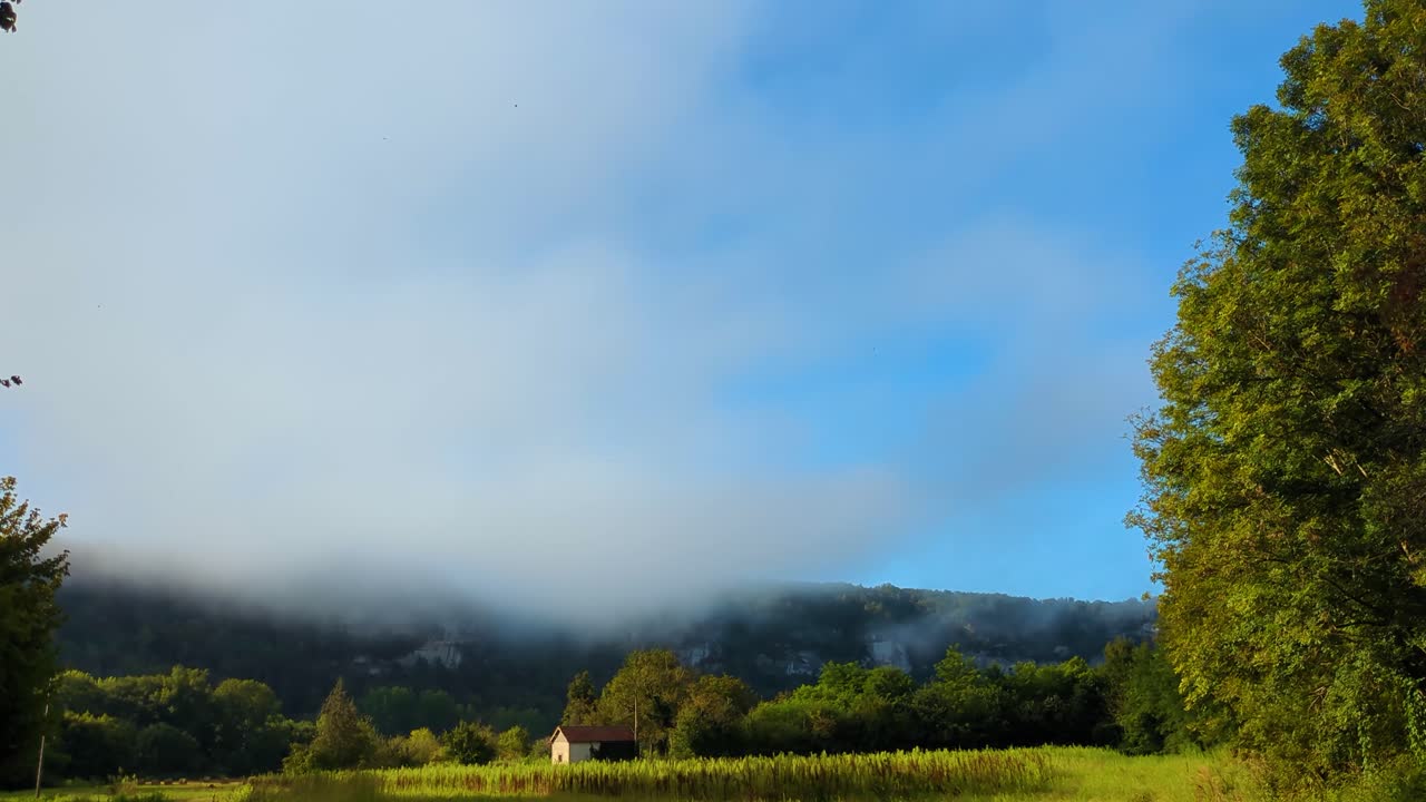 밝은 파란 하늘과 낮은 안개 구름과 배경 4k의 절벽과 함께 작은 농장 오두막을 가진 프랑스 시골의 전망