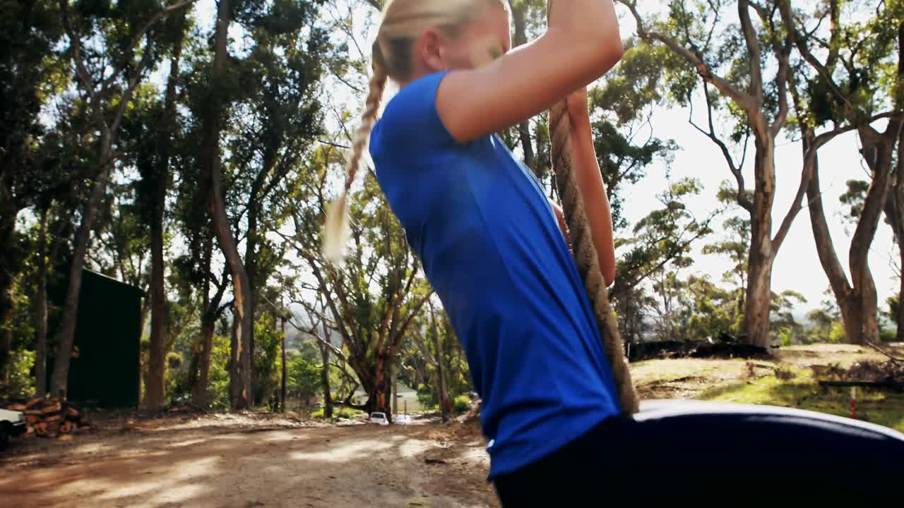 mujer en forma subiendo la cuerda durante una carrera de obstáculos