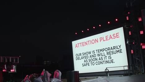 outdoor stage at night, sign delaying show until thunderstorm ends