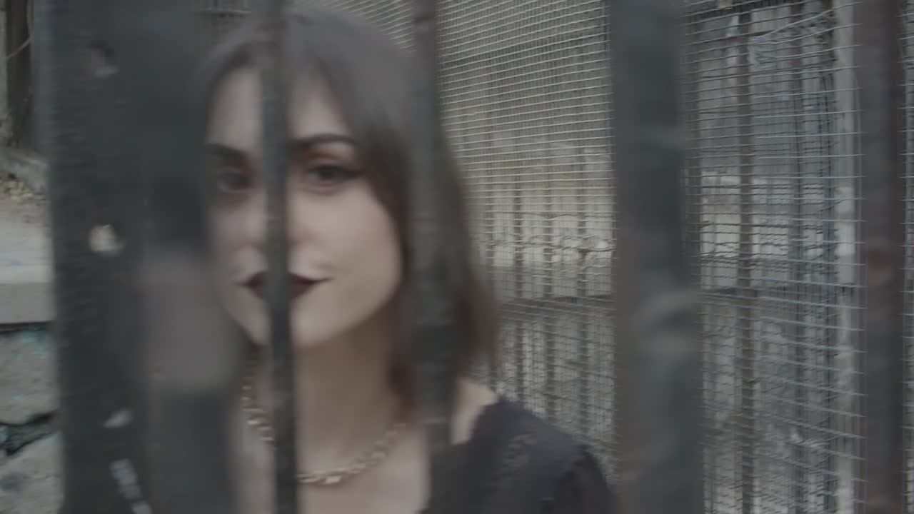 감금소 회색 톤에 갇힌 카메라를 무시하고 어두운 화장을 한 젊은 성인 여성