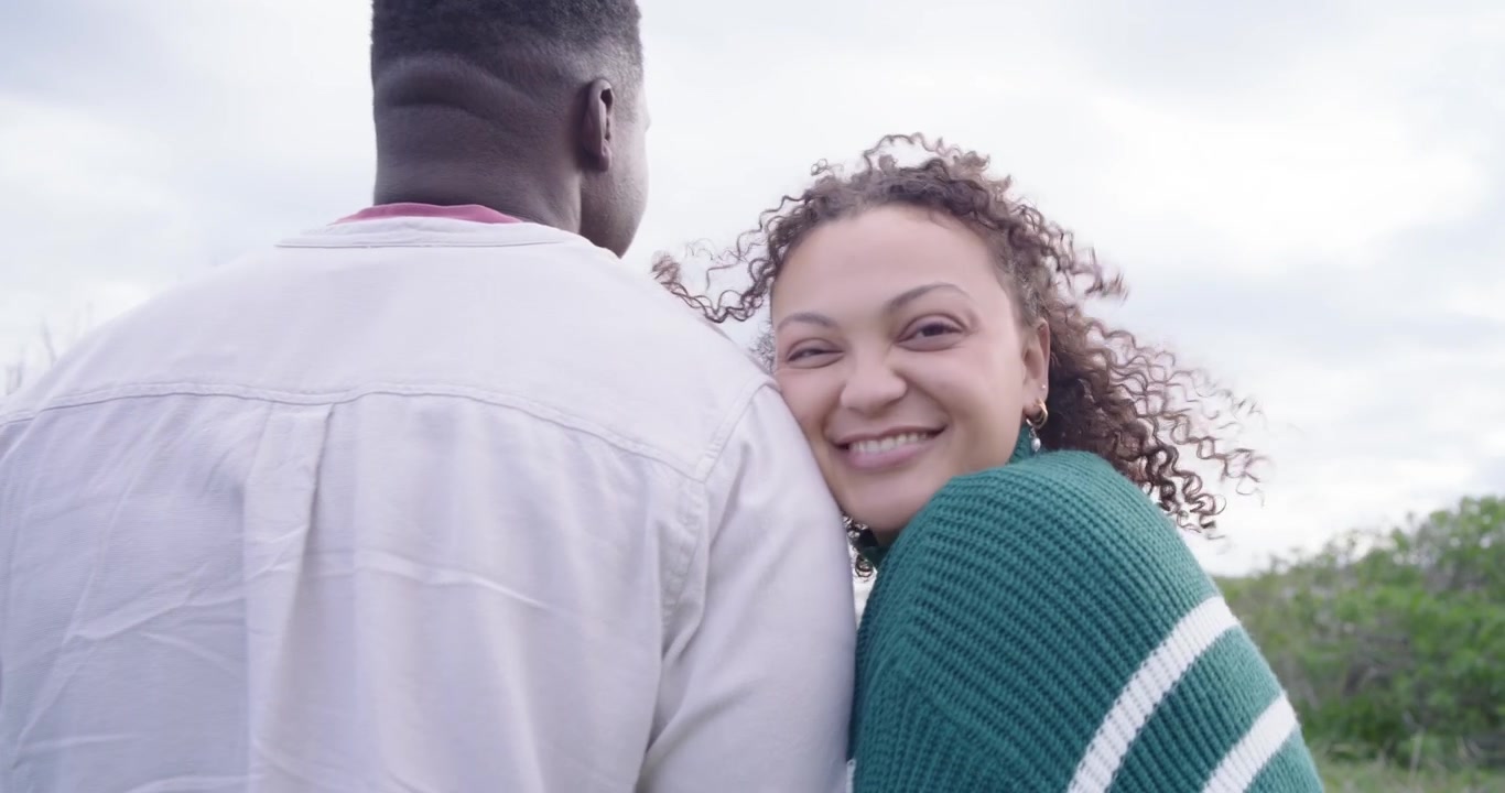 African American couple walking dunes woman pointing man leaning in green sweater talking about sea