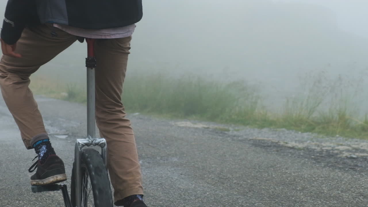 Through misty weather, rider glides, on a unicycle, where fog resides