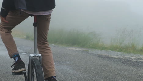 through misty weather, rider glides, on a unicycle, where fog resides