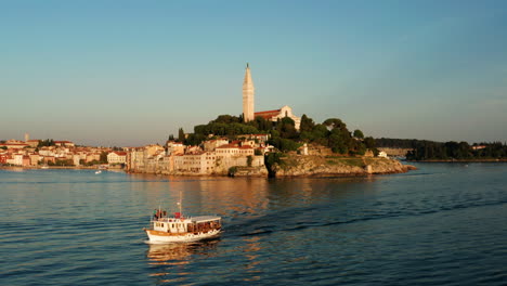 cruising fishing boat crossing on the seafront old city of rovinj in istria, croatia at sunset