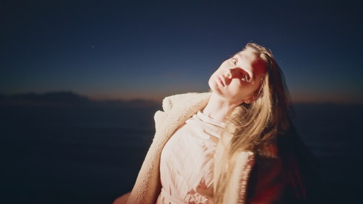 ragazza a luce al neon che balla a una festa notturna in spiaggia close-up. donna sottile e rilassata che muove il corpo