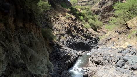 Hand-held-panning-upward-shot-of-a-small-stream-flowing-down-a-volcanic-landscape