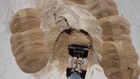 vista aérea de un tractor que mueve una carga de arena fresca en un sitio de construcción en 4k