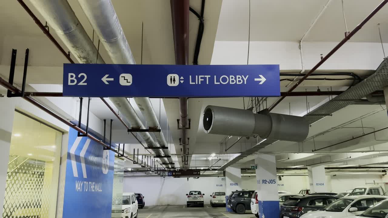 A tilt down shot showing Basement parking LED Direction Signs Board pointing lift and lobby