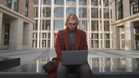 portrait of young confident businessman with laptop outdoors