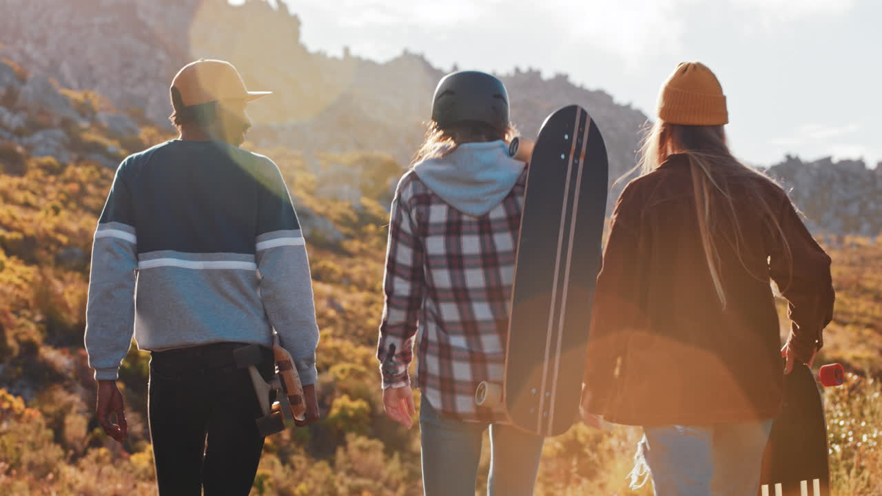 여러 민족의 스케이터 친구들이 롱보드를 들고 함께 여름 휴가를 즐기고 롱보드를 타고 시골 도로를  ⁇ 고 대화를 나누고 있습니다.