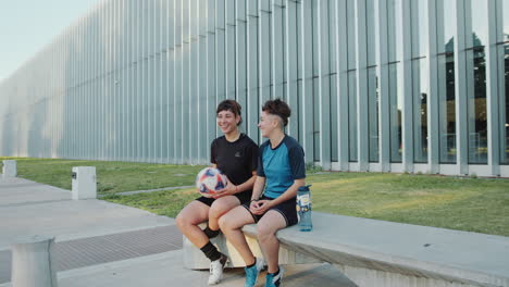 two girlfriends resting and speaking after playing soccer outdoors