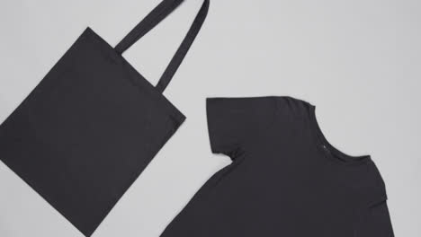 close up of black bag and t-shirt on white background, with copy space, slow motion