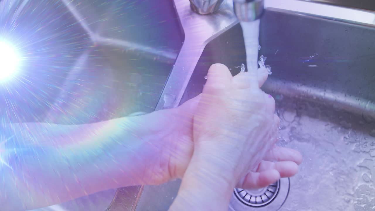 주방 싱크대에 손을  ⁇ 고 있는 고령 여성의 중간 부분을 가로질러 움직이는 빛의 애니메이션