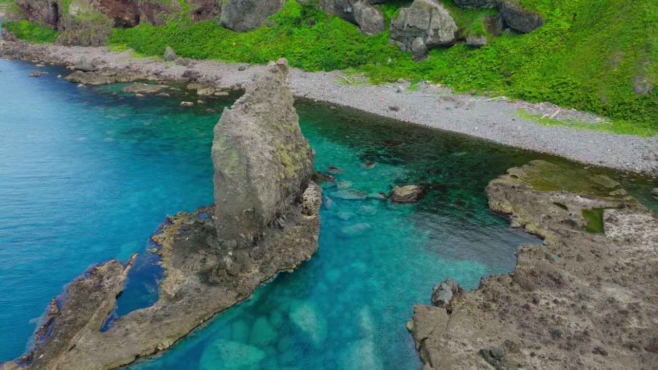 Aerial drone fly close to Japanese Cliff in Shakotan beach Hokkaido revealing sunrise skyline glow