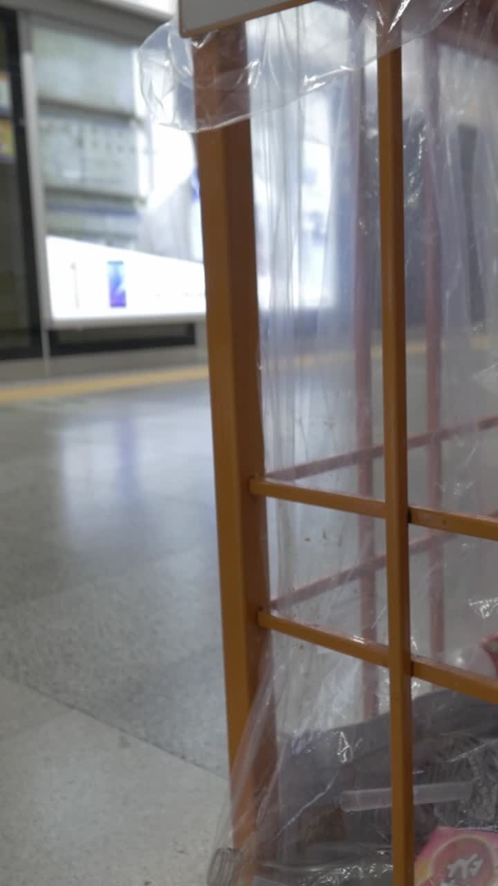 Persona che getta i rifiuti in un cestino pubblico in una stazione della metropolitana