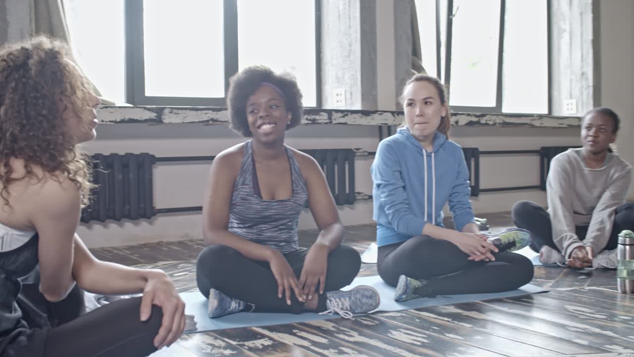 mujeres jóvenes charlando en clase de yoga